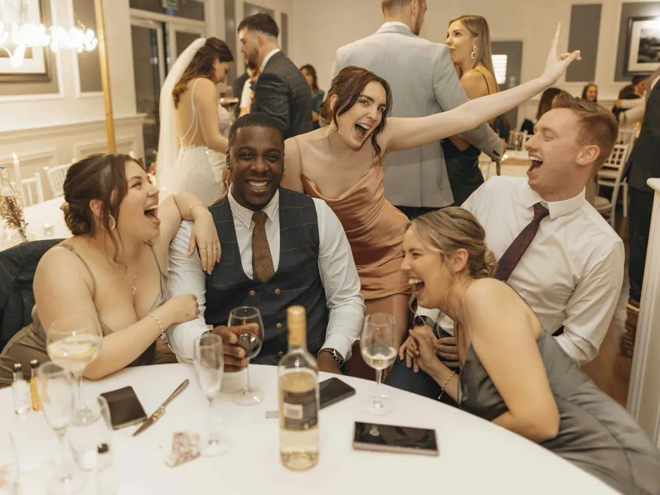 A table of guests laughing and raising their arms